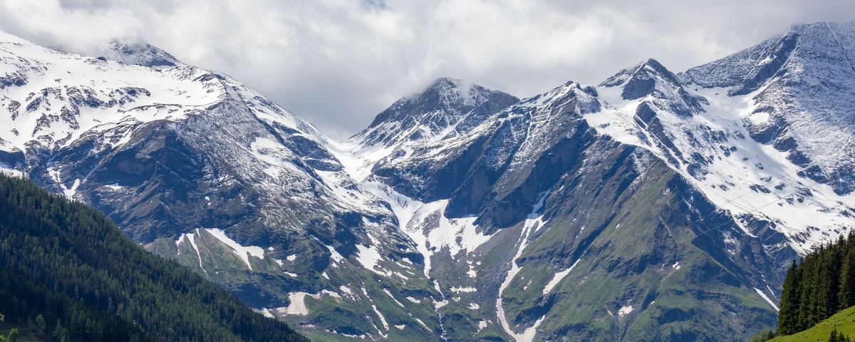 Snow-capped mountain range above a green alpine valley